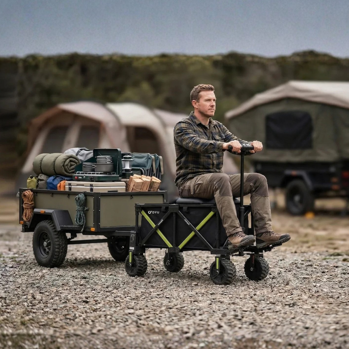 DYU Campx på grus med en man sittande på vagnen bredvid en lastad släpvagn och tält