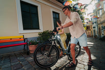 OneSport WT05 i sidovy, en man håller i styret medan en kvinna står bakom med en cykel på en gata med paraplyer