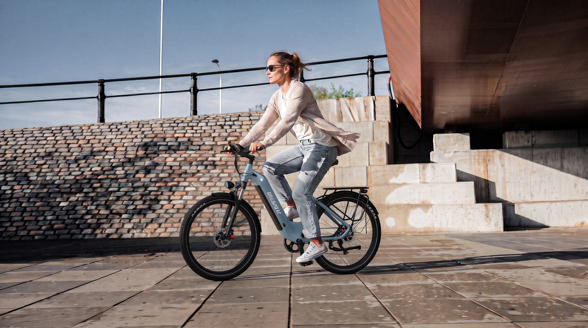 Kvinna cyklar på OneSport WT05 i sidovy framför en stentrappa och en tegelmur