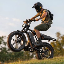 Förare gör ett hopp med TST R002 Plus fatbike-elcykel i färgen svart på en gräsplan