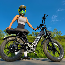 Kvinna står med TST R7 fatbike-elcykel i färgen svart på en gräsplan