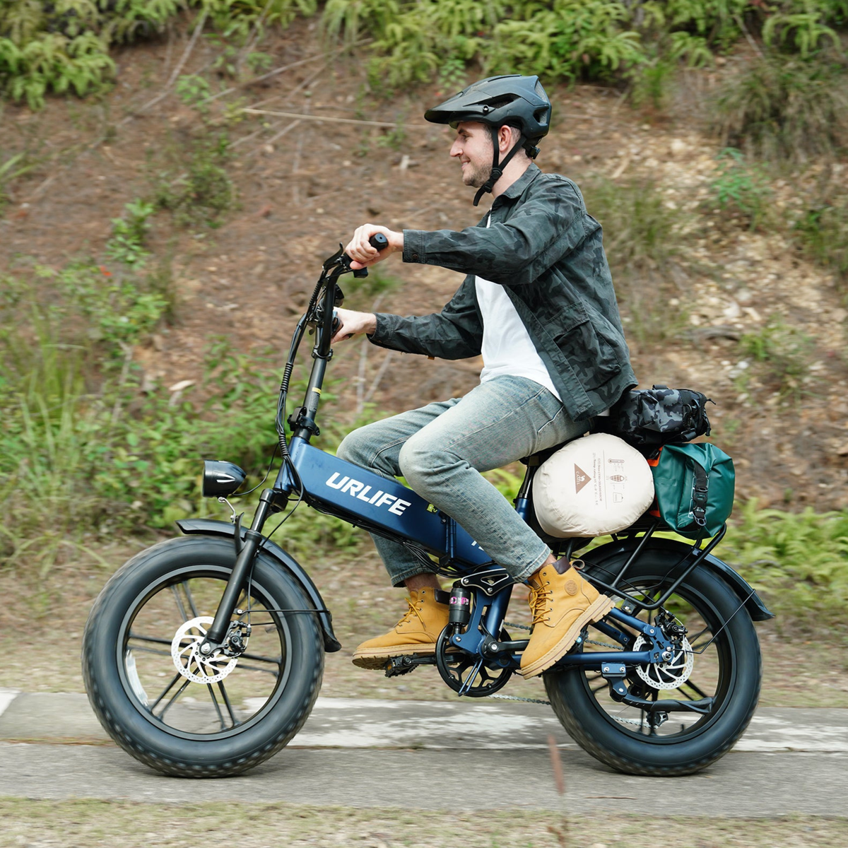 Man med hjälm cyklar på en URLIFE T5 med bagage bakom sadeln