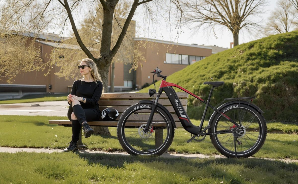 Person sitter bredvid Duotts F26 Lite fatbike-elcykel i en park