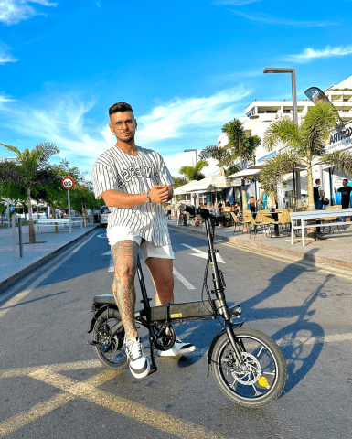 Man står med DYU A1F Pro hopfällbar elcykel i stadsmiljö