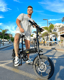 Man står med DYU A1F Pro hopfällbar elcykel i stadsmiljö
