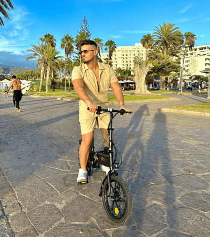 Man står med DYU A1F Pro hopfällbar elcykel i stadsmiljö