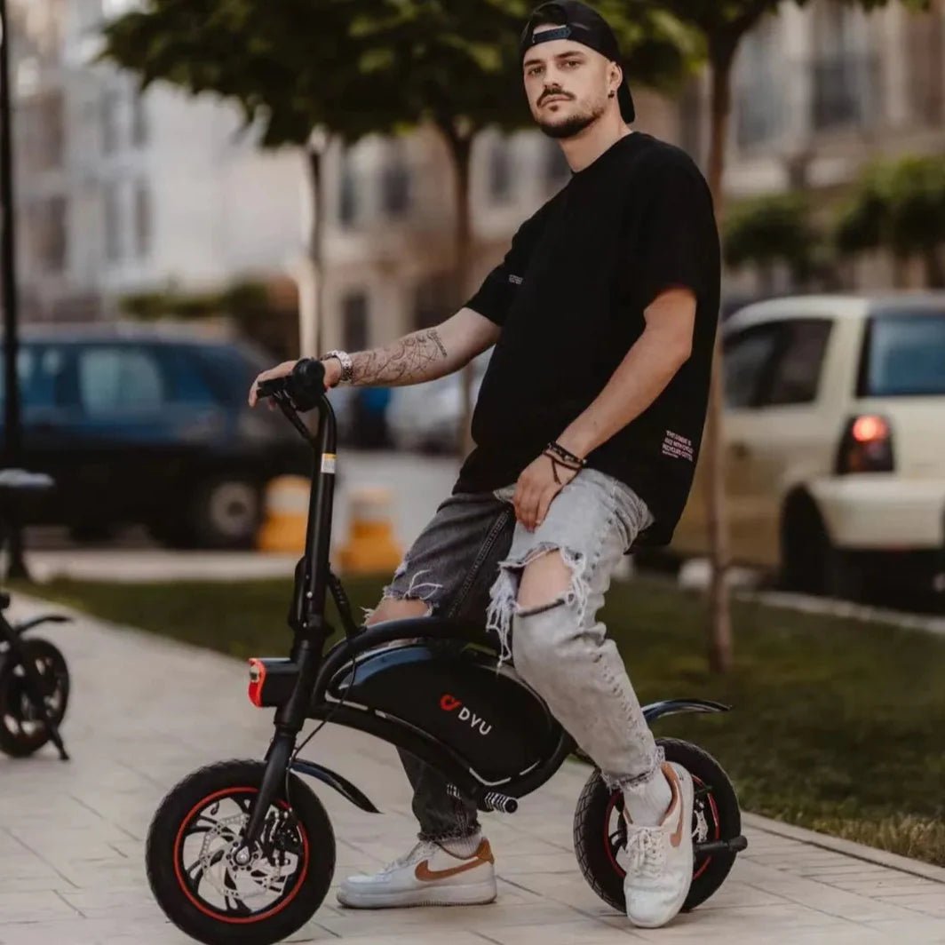 Man står med DYU D3S hopfällbar elcykel i stadsmiljö
