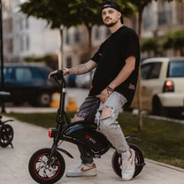 Man står med DYU D3S hopfällbar elcykel i stadsmiljö