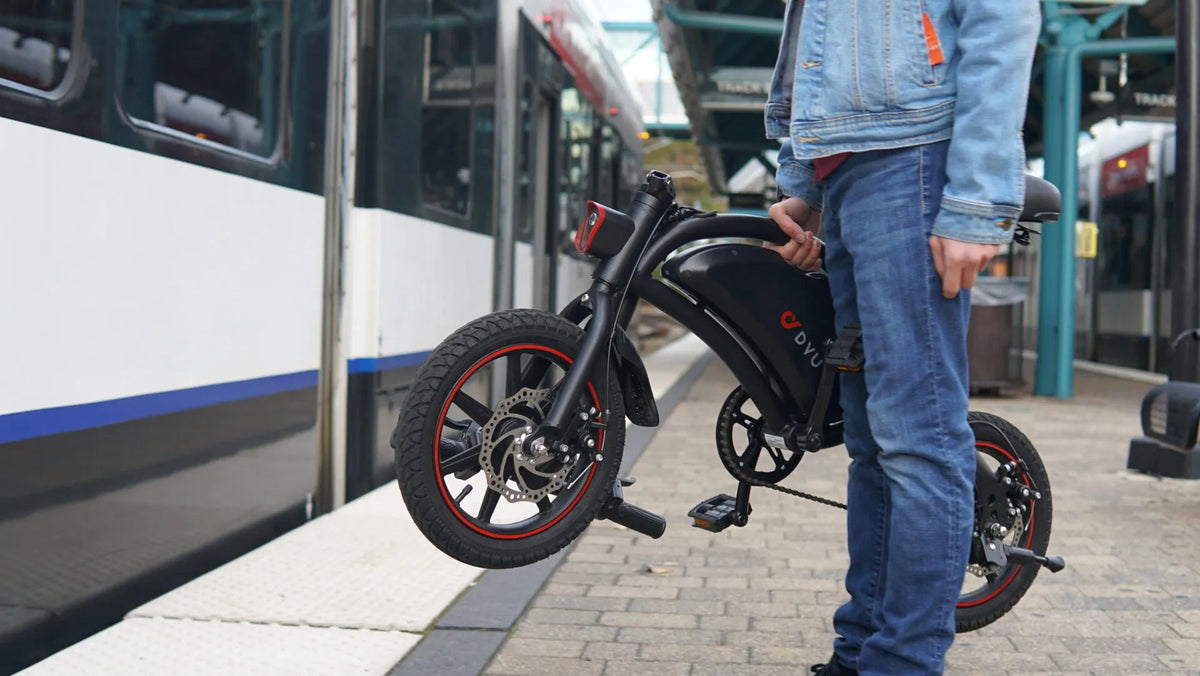 Man står med DYU D3S hopfällbar elcykel i stadsmiljö