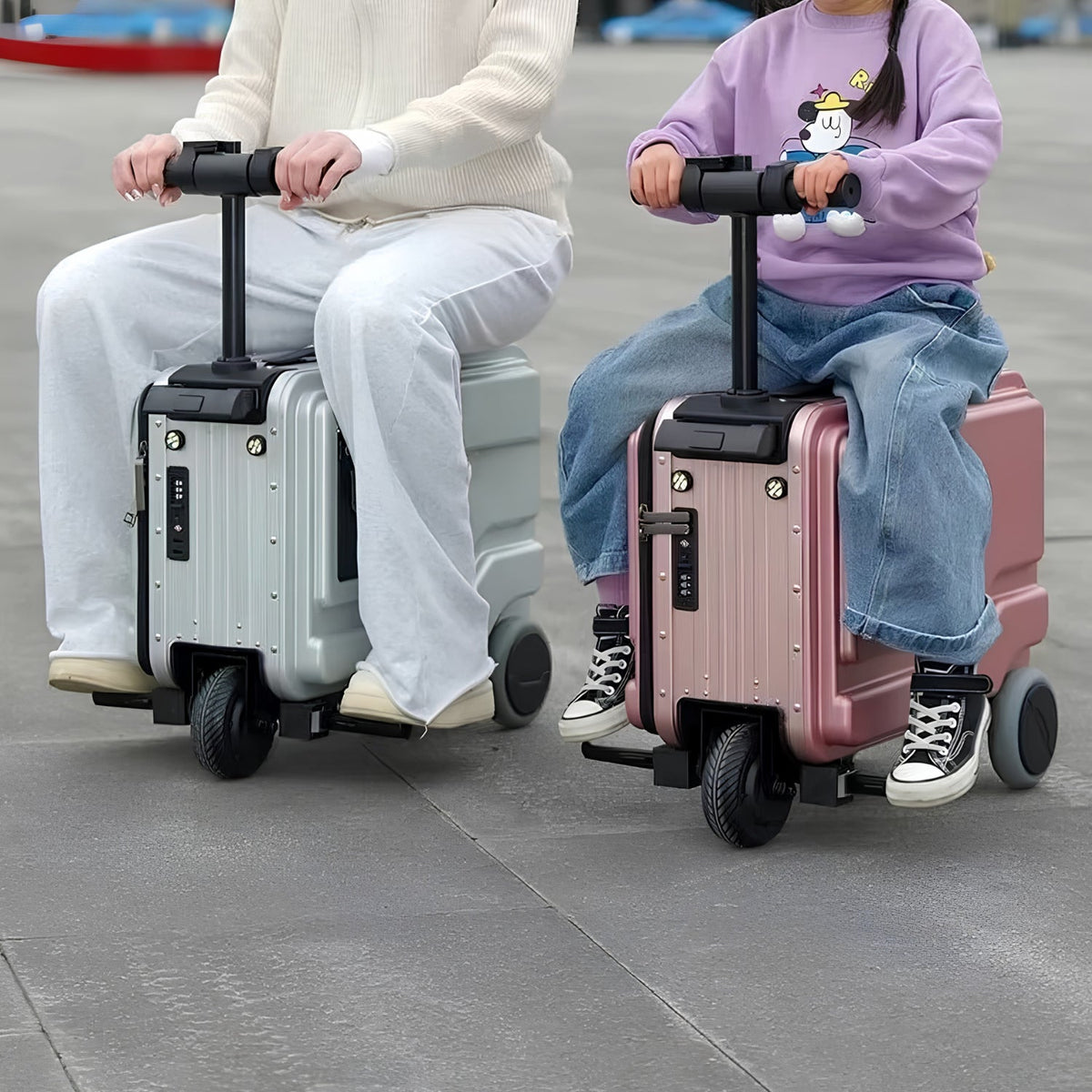 Två personer åker på varsin PowerDrive Pro Edition elektrisk åkbar resväska