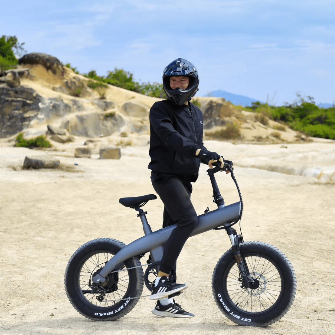 Man står med HX Q3 Plus fatbike-elcykel i sandig terräng