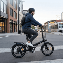 Man som kör Onemile E2 hopfällbar elcykel på en väg
