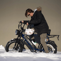 Man står med Onemile P40 Pro fatbike-elcykel med hjälm i vintermiljö