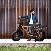 Man står med Onemile P40 Pro fatbike-elcykel i färgen orange i solsken