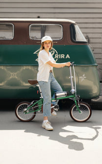 Kvinna står med OneSport OT02 hopfällbar elcykel på en gata