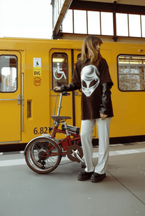Kvinna står med OneSport OT02 Pro hopfällbar elcykel i färgen röd på en gata