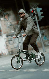 Man som kör OneSport OT02 Pro hopfällbar elcykel i färgen grön på en gata