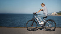 Person som kör OneSport OT05 Pro elcykel med hjälm vid havet i färgen ljusblå