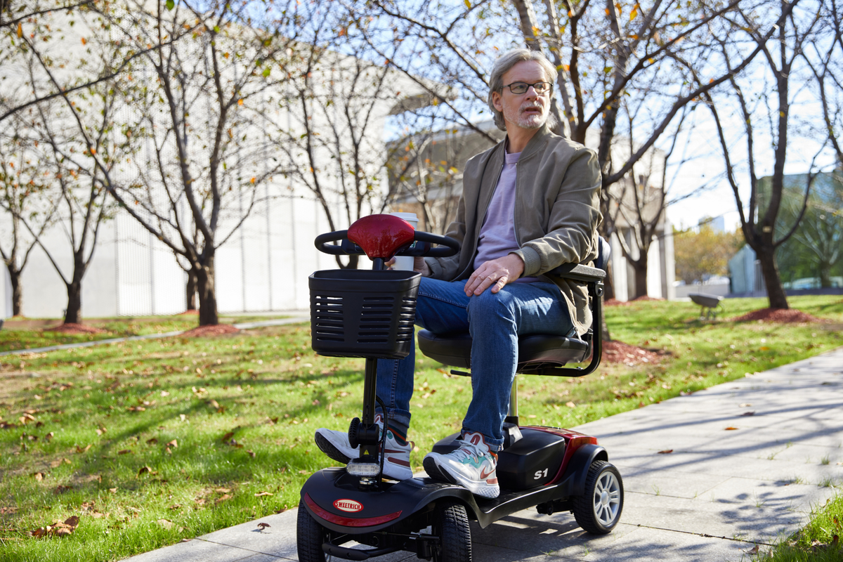 Man sitter på Sweetrich S1 Sport permobil i en park