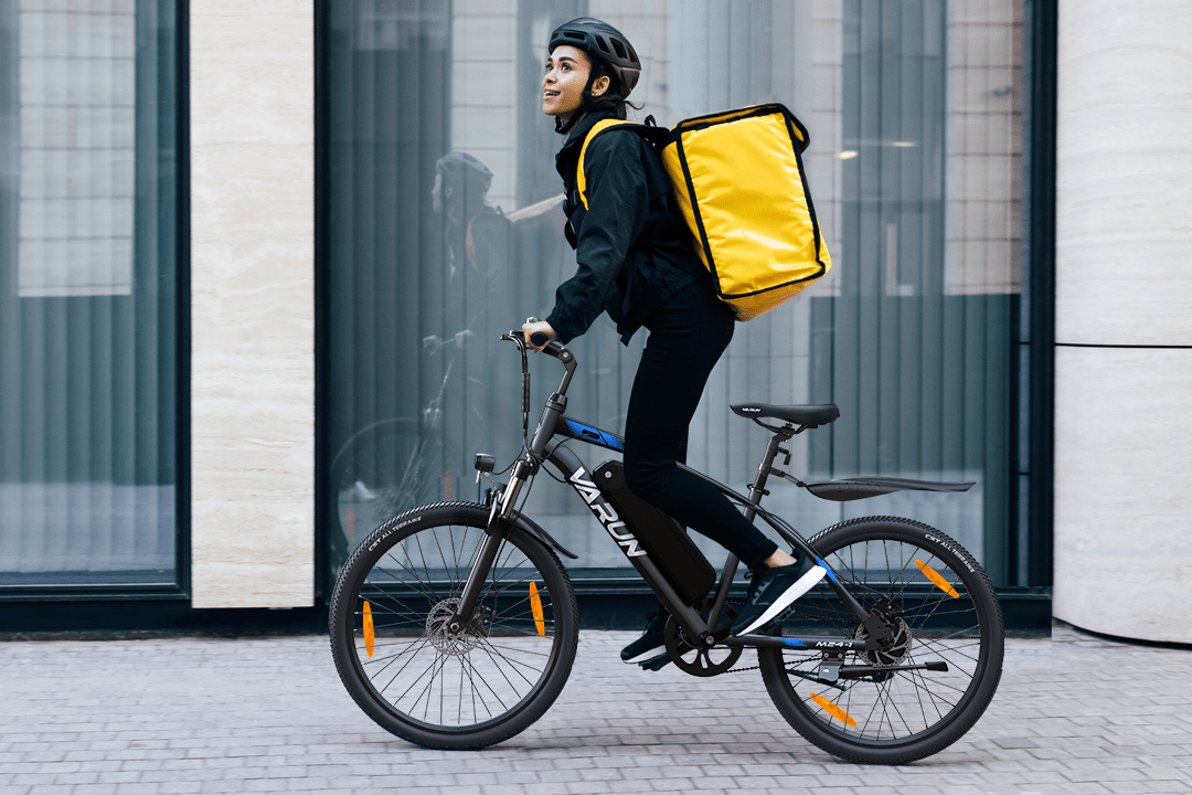Person som kör VARUN M24-1 elmountainbike i färgen svart med hjälm i stadsmiljö
