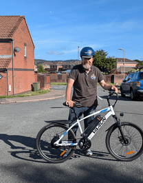 Man står med VARUN M24-1 elmountainbike i färgen vit med hjälm på en gata