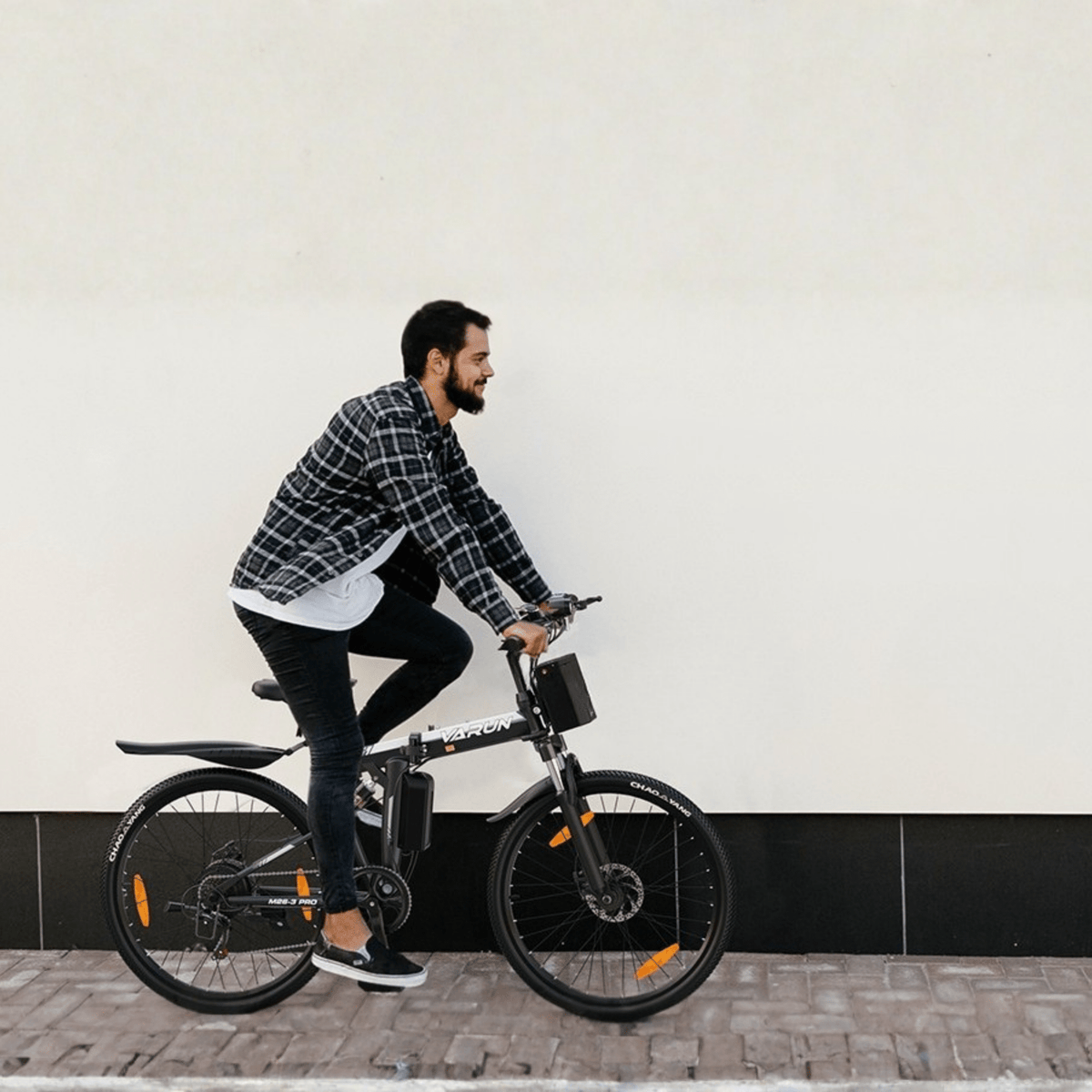 Man som kör VARUN M26-3 Pro elmountainbike i färgen svart på en gata