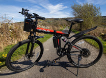 VARUN M26-3 Pro elmountainbike snett framifrån i färgen svart parkerad på en gångväg