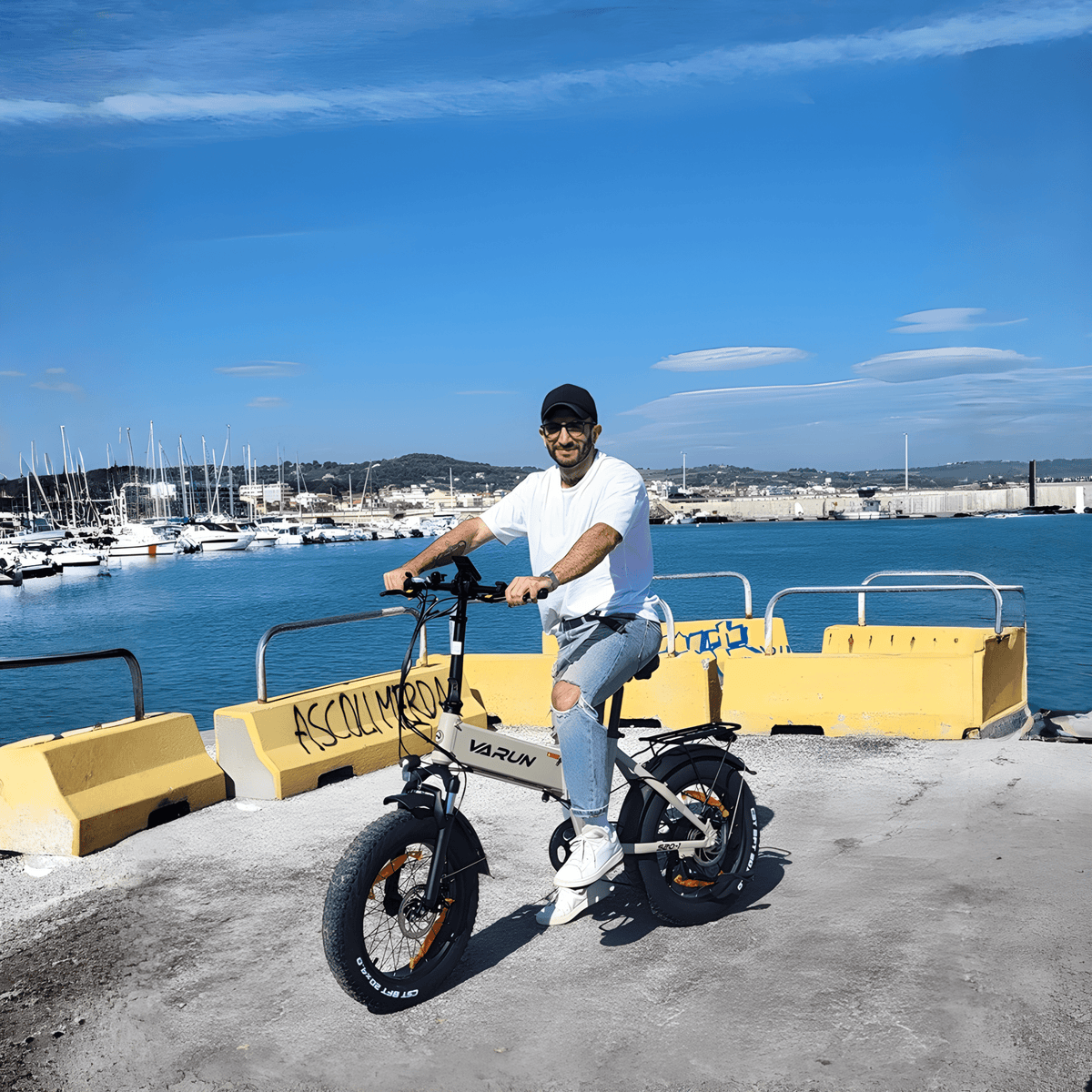 Man som kör VARUN S20-1 hopfällbar fatbike-elcykel i färgen beige vid havet