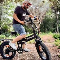 Man som kör VARUN S20-1 hopfällbar fatbike-elcykel i färgen svart i skogen