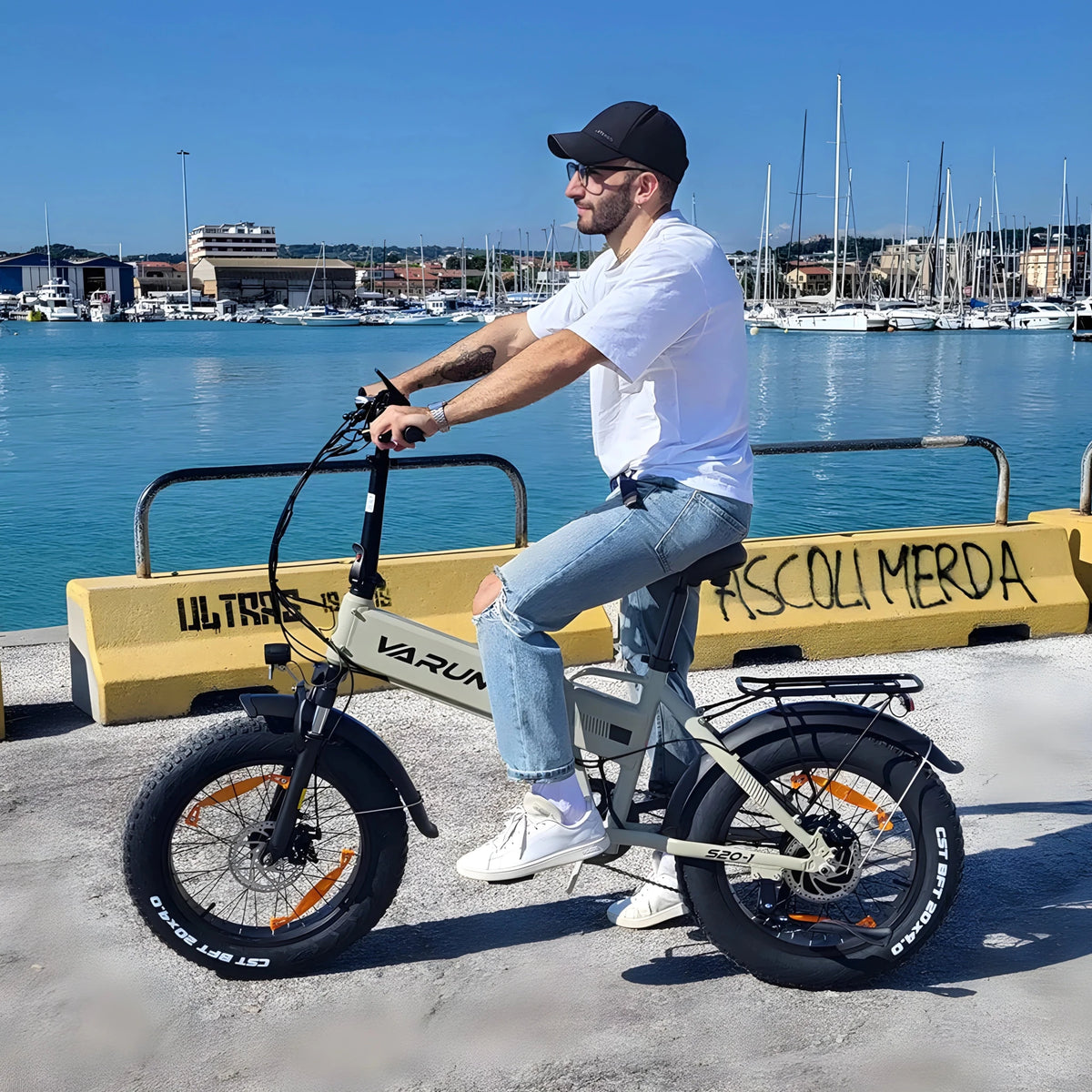 Man sitter på VARUN S20-1 hopfällbar fatbike-elcykel i färgen beige vid havet