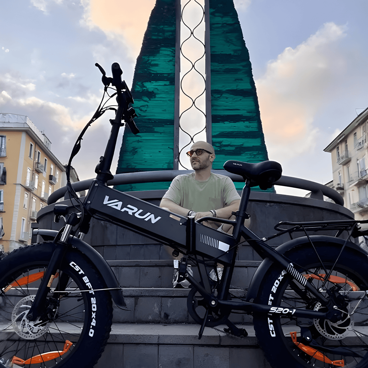 Man står med VARUN S20-1 hopfällbar fatbike-elcykel i färgen svart i stadsmiljö
