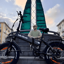 Man står med VARUN S20-1 hopfällbar fatbike-elcykel i färgen svart i stadsmiljö