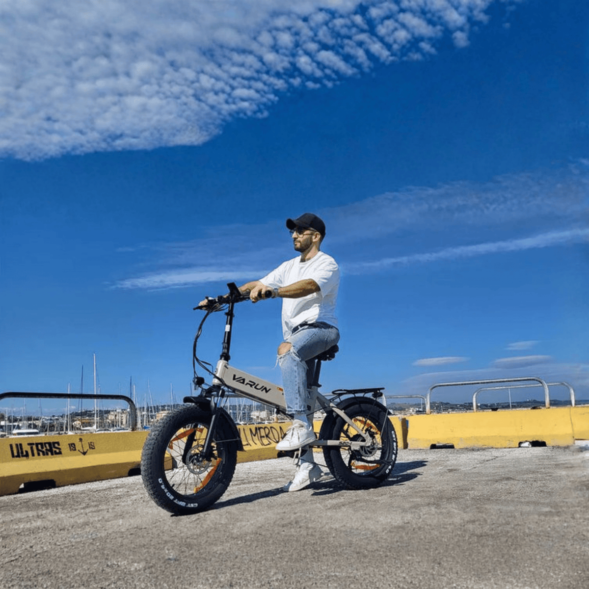 Man som kör VARUN S20-1 hopfällbar fatbike-elcykel i färgen beige vid havet