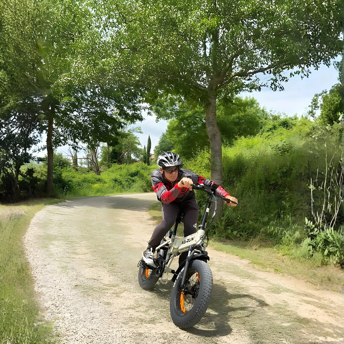 Man som kör VARUN S20-1 hopfällbar fatbike-elcykel i färgen beige med hjälm på en gångväg