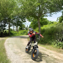 Man som kör VARUN S20-1 hopfällbar fatbike-elcykel i färgen beige med hjälm på en gångväg