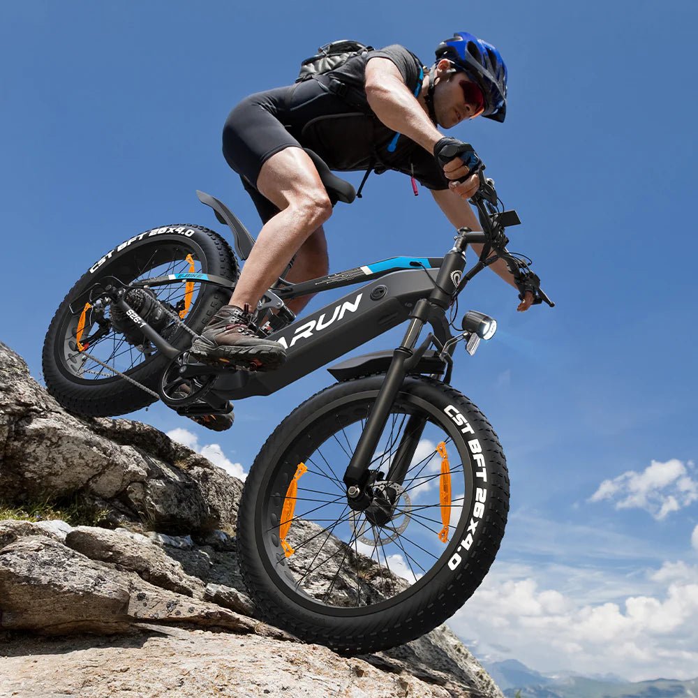 Förare kör VARUN S26-1 fatbike-elcykel i terräng med hjälm i bergsmiljö