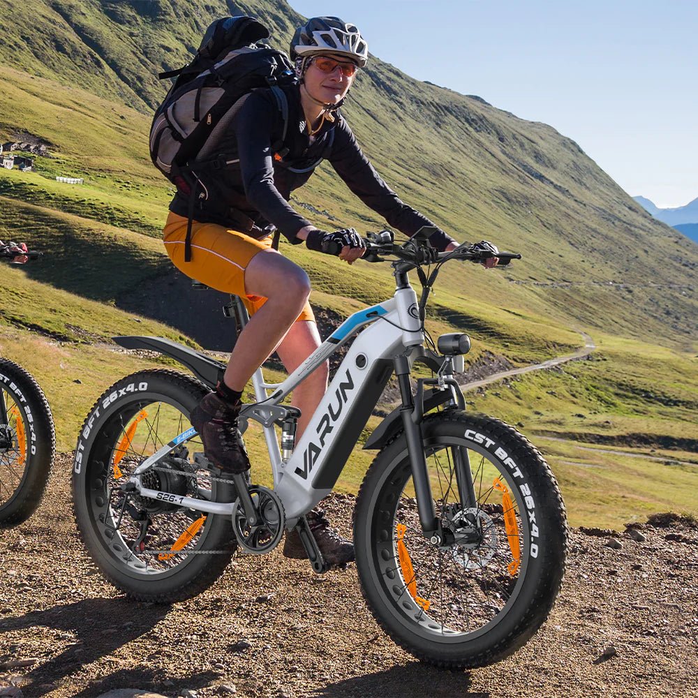 Man som kör VARUN S26-1 fatbike-elcykel i färgen vit med hjälm i bergsmiljö