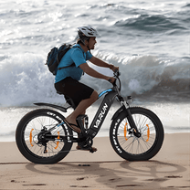 Man som kör VARUN S26-1 fatbike-elcykel i färgen vit vid havet