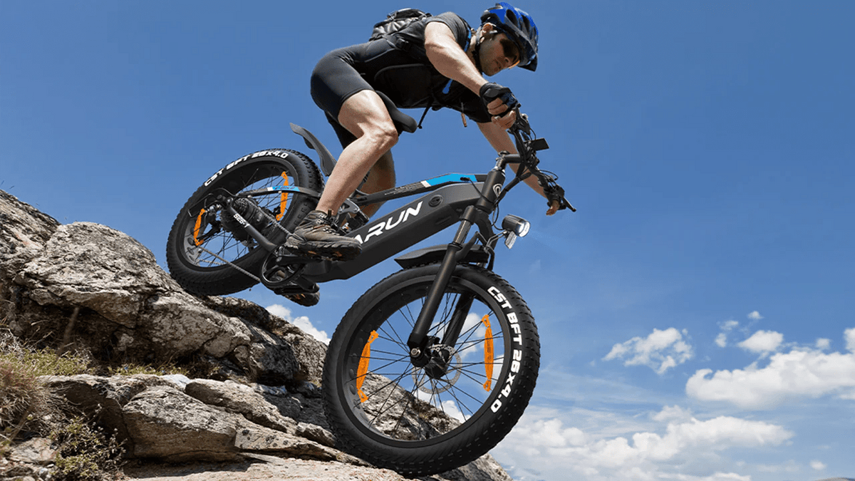 Förare gör ett hopp med VARUN S26-1 fatbike-elcykel med hjälm i bergsmiljö