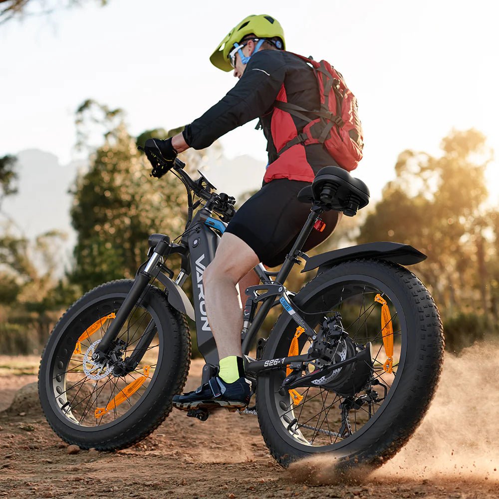 Man som kör VARUN S26-1 fatbike-elcykel i färgen svart med hjälm på en stig