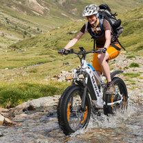 Förare kör VARUN S26-1 fatbike-elcykel i terräng med hjälm på en gräsplan