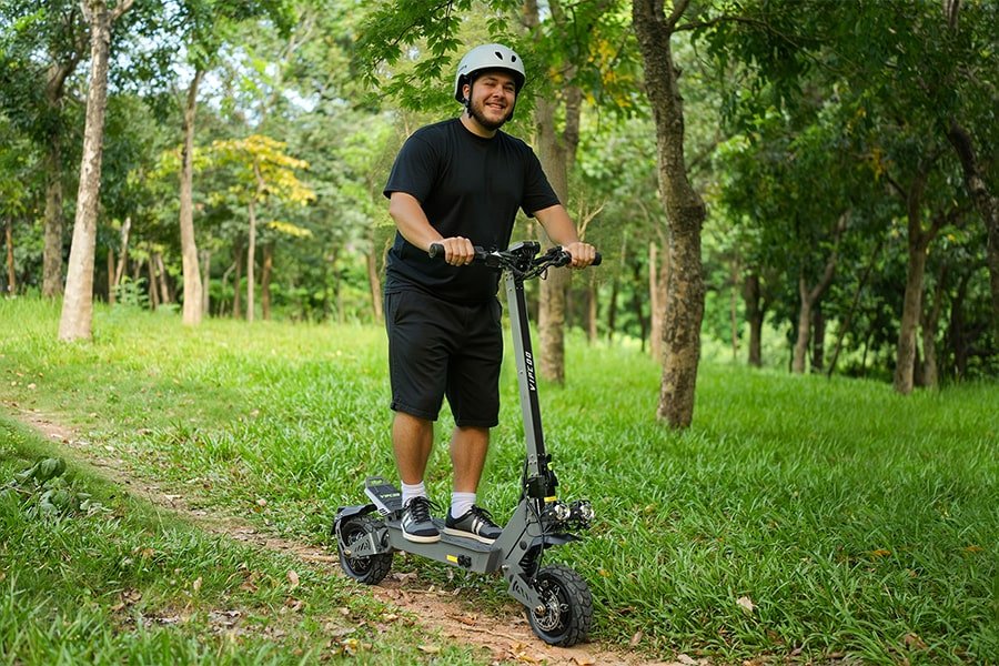 Man står med VIPCOO VS9 elsparkcykel i en park