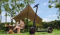 Person sitter bredvid Xiaomi 4 Pro Nordic Edition elsparkcykel i en park